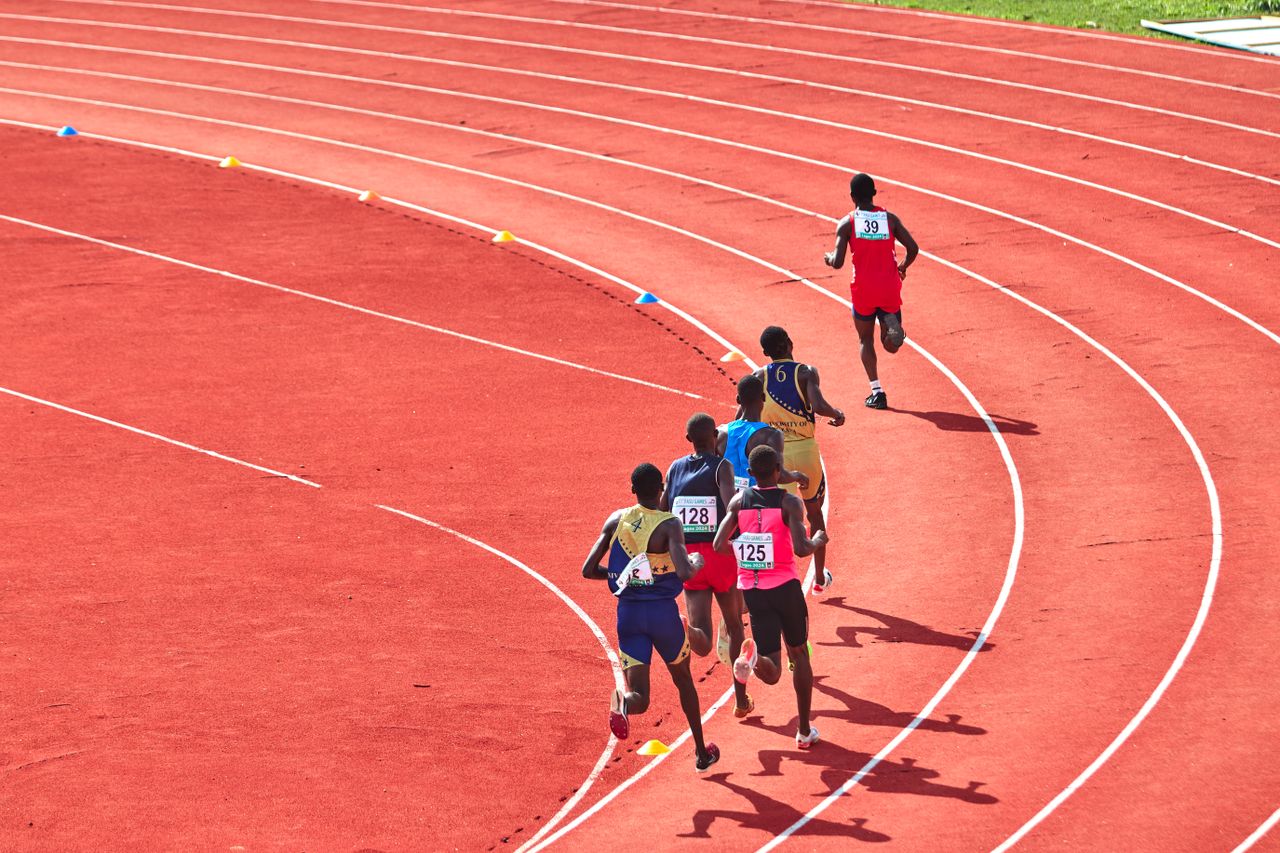 footer-cta-img A group of athletes running on a curved outdoor track in a competitive race.